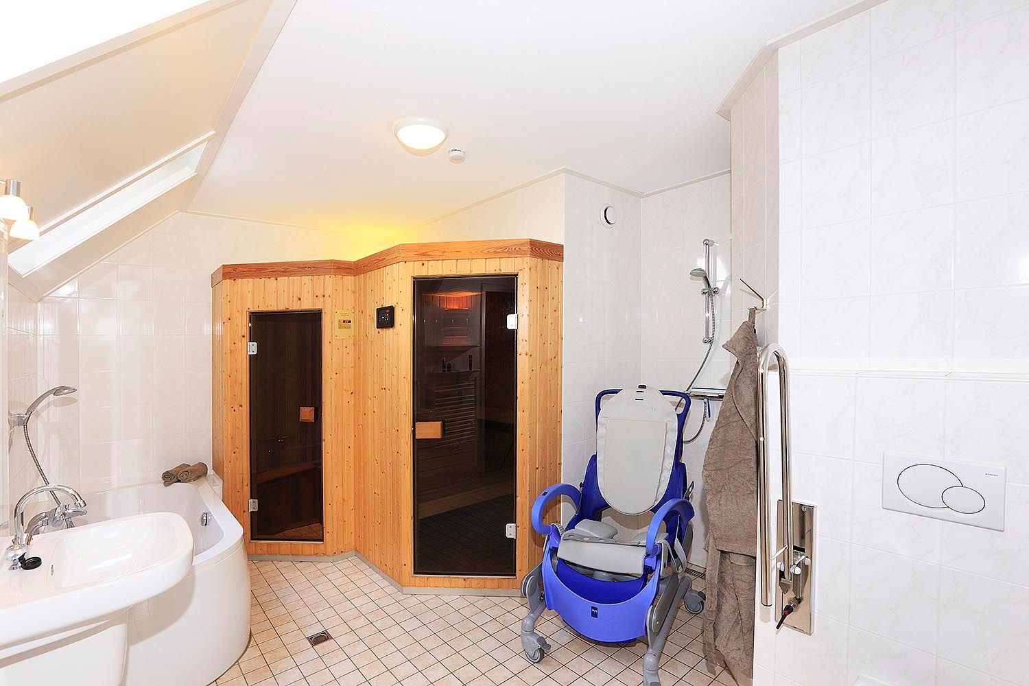 Badkamer met douchestoel en sauna